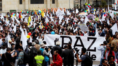 Demonstranter som stöder fredsprocessen håller upp ett stort plakat med ordet fred under en demonstration i Bogota.
