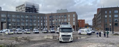 Ett tiotal polisbilar uppradade på en grusplan intill nya våningshus som byggs. 