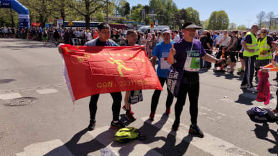 Kinesiska löpare står med en flagga innan loppet