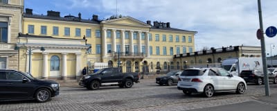 Bilar på gatan framför Presidentens slott i Helsingfors.
