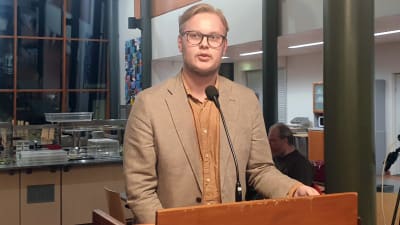 Aleksi Kurki står i ett talarbås.