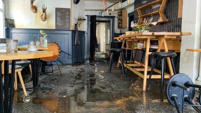 En förstörd restaurang med vatten och sotsörja på golvet. 
