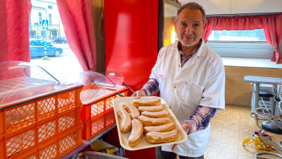 En man håller i en bricka med avlånga berlinermunkar.