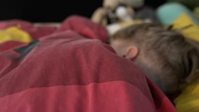 Barn som sover i en säng.