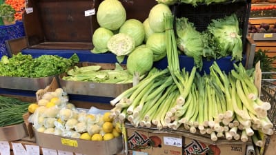 En butikshylla med grönsaker.