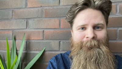 Skäggig man ser in i kameran