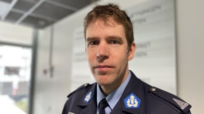 Mansperson i polisuniform, i bakgrunden skyltning för Vasa polisstation.