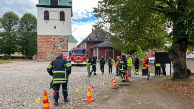 Brandmän och civiler står utanför Borgå Domkyrka och kållar på sprinklersystemet i gång.
