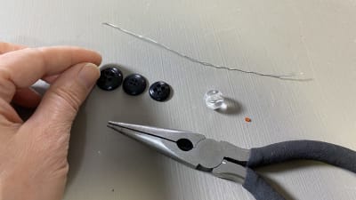 En hand, en tång, några knappar och pärlor