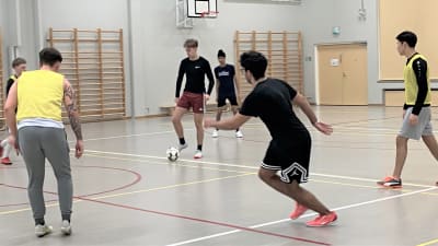 Nuoret miehet pelaavat futsalia Lahdessa koulun liikuntasalissa. 