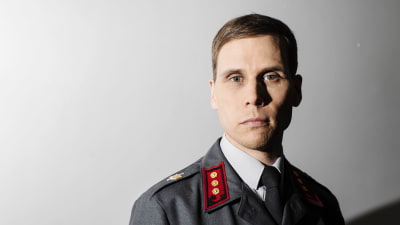 En man i militäruniform stirrar stint in i kameran.
