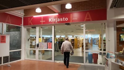 Mies kulkee kohti kirjaston sisäänkäyntiä.