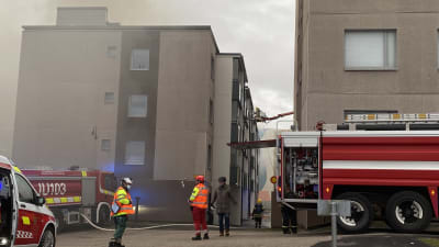 Brandmän framför ett rykande höghus.