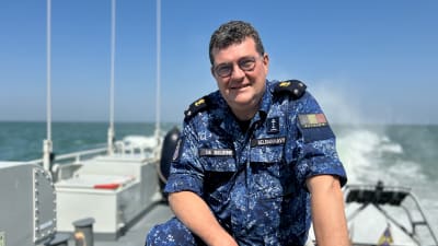 Belgisk amiral ombord på patrullfartyg tittar leende in i kameran