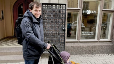 Man som står och håller i en barnvagn.