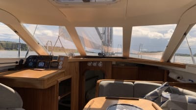 Interiören på en segelbåt med träpaneler och mycket fönster. 