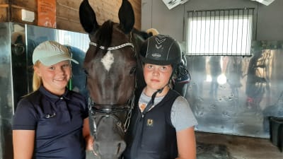 Stallflickorna Roosa Piiri och Henna Näätänen med hästen Clara i Hangö udds ryttares stall.