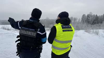 Två gränsövervakare fotade bakifrån står i ett vintrigt landskap vid östgränsen. 