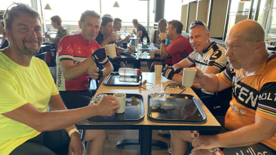 Ett gäng cyklister sitter och dricker kaffe.
