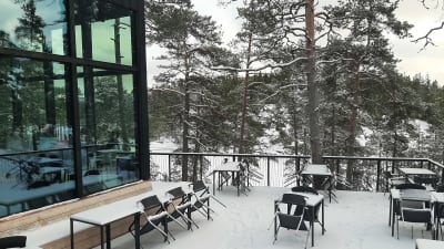 Snötäckt terrass med tallar i bakgrunden vid restaurang The Berg i Barösund.