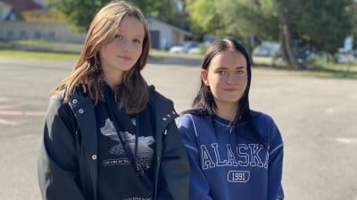Två tonårsflickor på en sandplan.