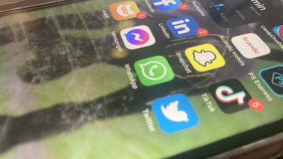 En telefonskärm med ikoner för appar på olika sociala medier synliga. Skärmen är skråmig.