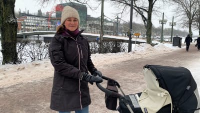 Linda står med en barnvagn vid Aura å i Åbo 