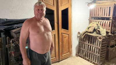 Jordbrukaren Serhij Sjevtsjenko är en gråhårig man som står med bar överkropp intill en trave med glesa lådor.