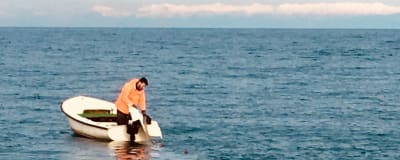 En kroatisk fiskare lägger ut nät från sin lilla båt.