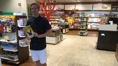 En man står med en nyinköpt Harry Potterbok i handen.