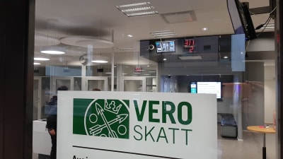 En skylt med texten Vero Skatt, på glasdörren in till ett skattekontor.