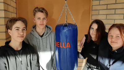 Juhana Virkkunen, Georg Sarlin, Julia Adolfsson och Olga Åberg, fyra ungdomar från Nagu står kring en boxningssäck.