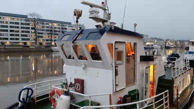 Styrhytten på en blåvit sjöbuss är upplyst en smådimmig morgon i Aura å i Åbo.