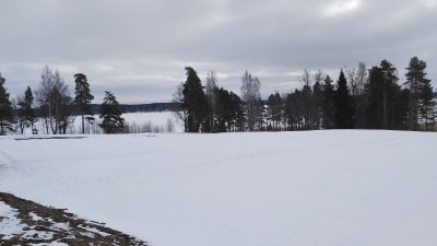 Snöigt landskap med frusen sjö i bakgrunden.