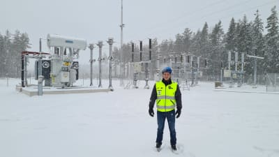 En man i skyddsväst och hjälm står i snön utanför en elstation. Han heter Andreas Talling.