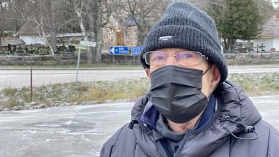 Äldre man med glasögon, svart möss och munskydd. 
