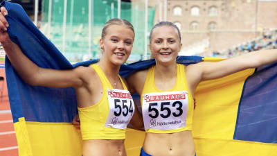 Nora Lindahl (t.h.) och Ella Borg (t.v.) poserar på Stockholms stadion draperad i den svenska flaggan.