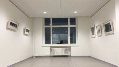 Ett fönster och vita väggar med tavlor.