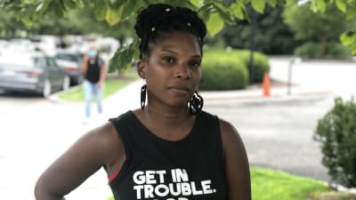 En kvinna står på gatan i Washington med en t-shirt där det står "get in trouble. necessary trouble."