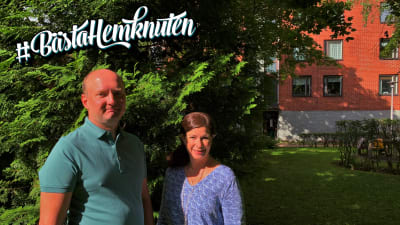 Sebastian Perret och Annika Roos står framför en grön buske, med ett rött tegelhus i bakgrunden, och ser in i kameran. Solen lyser i deras ansikten. Sebastian har inget hår, och en grön skjorta. Annika har långt, brunt hår och en blå klänning.