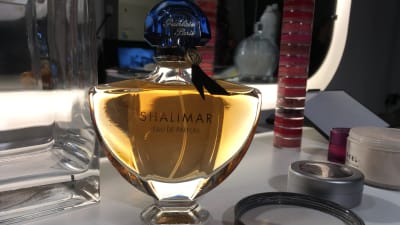 En flaska Shalimar-parfym på ett sminkbord.