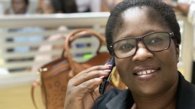 Jessie håller en mobiltelefon mot örat. Hon har jobbat på Lifeline/Childline Zambia i fem år. 