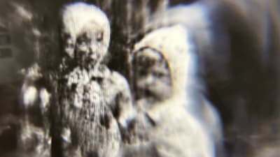 Epäselvä kuva kahdesta lapsihahmosta, valokuva tietokoneruudun läpi vanhasta lasinegatiivista.