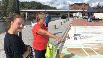 Stor karta över Borgå målad på asfalt som beundras av två personer.