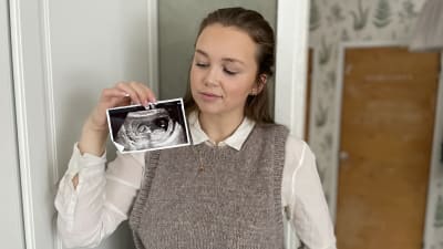En kvinna som tittar på en ultraljudsbild av ett foster.