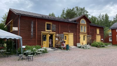 Ett rött stockhus med gula dörrar som fungerar som café.