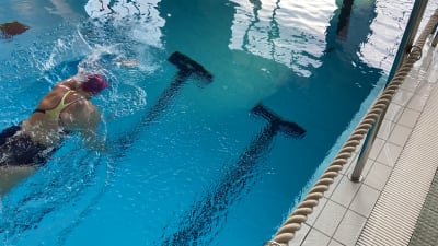 En person simmar i en simbassäng.