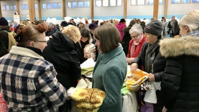 Människor som trängs kring lådorna av textilavfall.