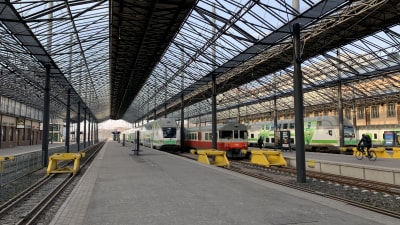 På bilden syns tre stycken tåg som står vid Järnvägstorget. Himlen är blå.