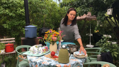 Ulla Erjala står och diskar vid sitt trädgårdsbord i Kuppis koloniträdgård i Åbo